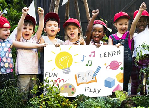 Happy students holding up a poster with the words, fun, learn, play