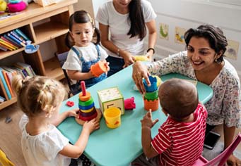 children and teachers at a table with toys