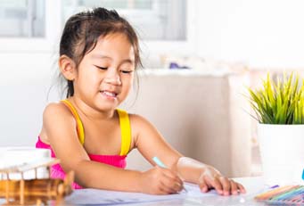 preschooler using crayons at a table