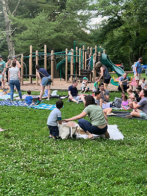 People sitting on blankets on the ground by a playground